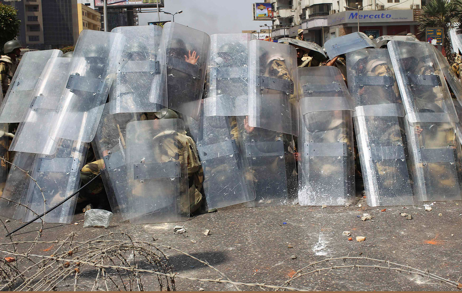 Riot police and army soldiers protect themselves with riot shields as members of the Muslim Brotherhood and supporters of ousted Egyptian President Mohamed Mursi throw stones during clashes around the area of Rabaa Adawiya square, where they are camping, in Cairo, Aug. 14, 2013.