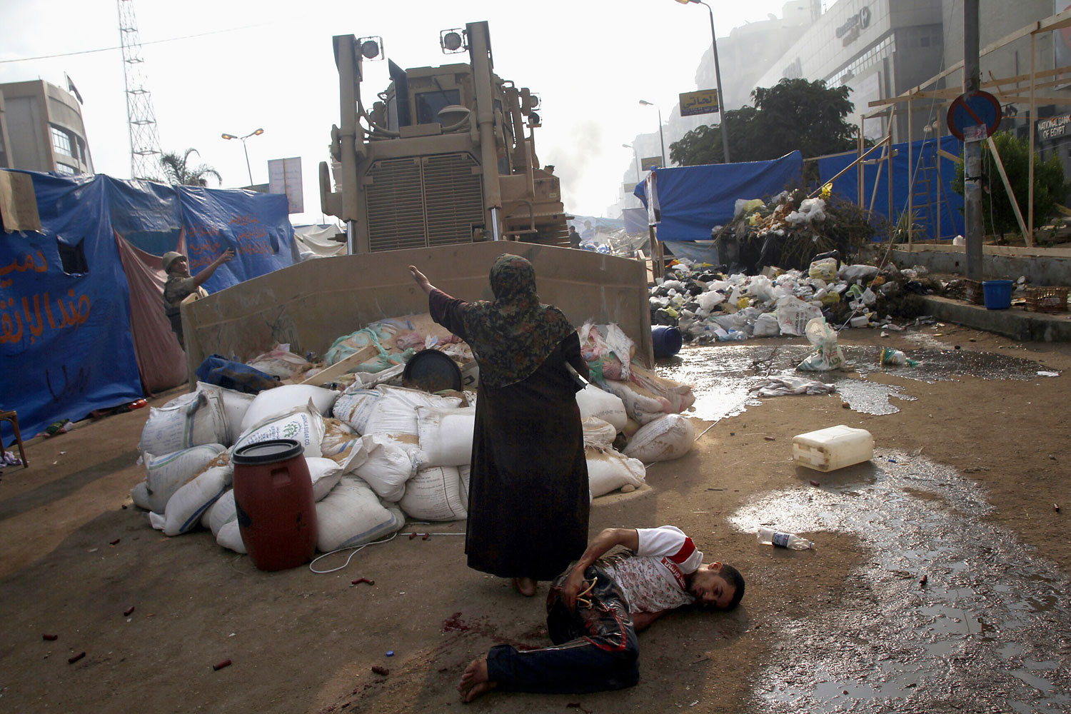 An Egyptian woman tries to stop a military bulldozer from hurting a wounded youth during clashes that broke out as Egyptian security forces moved in to disperse supporters of Egypt's deposed president Mohamed Morsi in a huge protest camp near Rabaa al-Adawiya mosque in eastern Cairo on Aug. 14, 2013.
