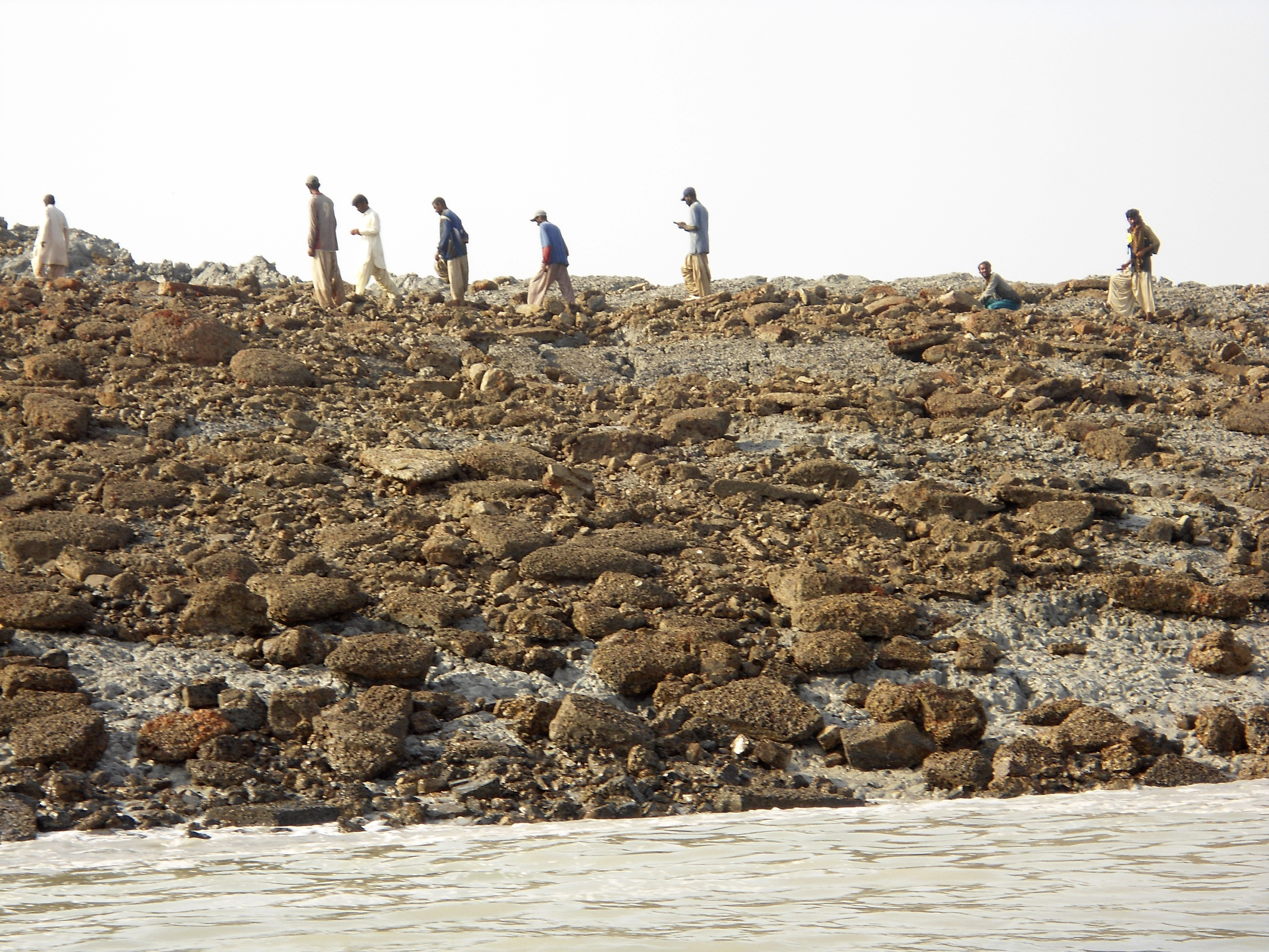 People walk on an island that rose from the sea following an earthquake, off Pakistan's Gwadar coastline in the Arabian Sea