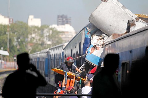 Rescue workers extract a passenger from a commuter train that crashed into the Once train station at rush hour in Buenos Aires