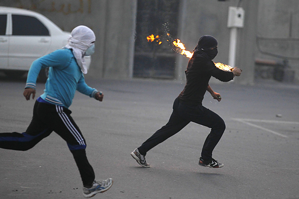 Anti-government protesters runs towards riot-police holding Molotov cocktails during clashes in the village of Diraz, west of Manama