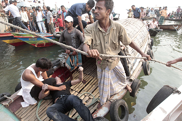 Volunteers load the body of a victim on a boat after a ferry capsized on the river Meghna in Munshiganj district