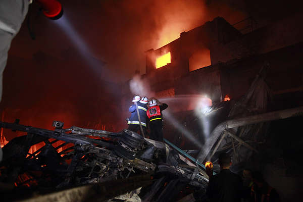 Palestinian fire fighters work to extinguish a fire at a building following an Israeli air strike in Gaza City