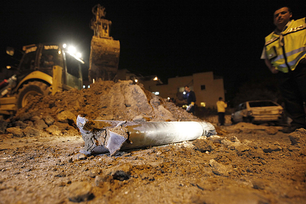 A security official stands next to a Grad rocket which was fired from Gaza and landed in Netivot in southern Israel