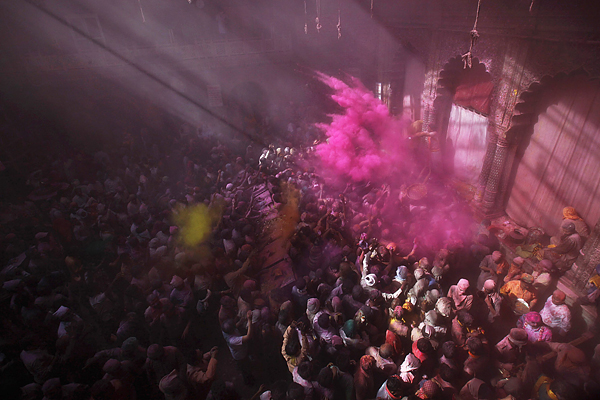 People throw coloured powder as they chant religious slogans inside a temple while celebrating the Holi in Vrindavan