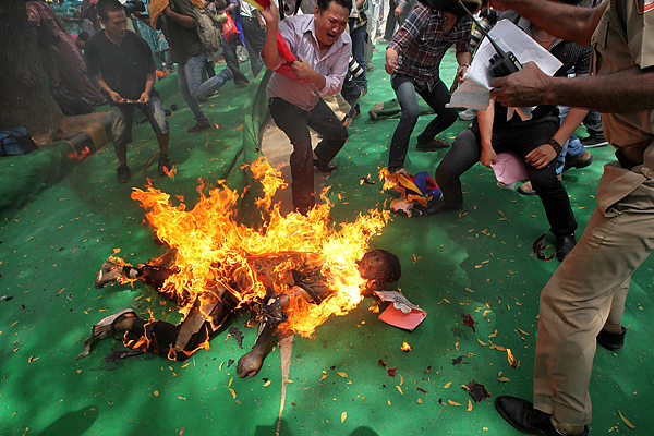 Tibetan protesters  and Indian policeman (L) dousing the fire of A Tibetan exile after  he set fire to himself in New Delhi