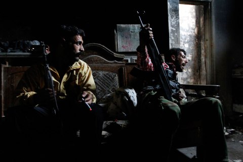 Free Syrian Army fighters carrying their weapons, sit inside a house in old Aleppo