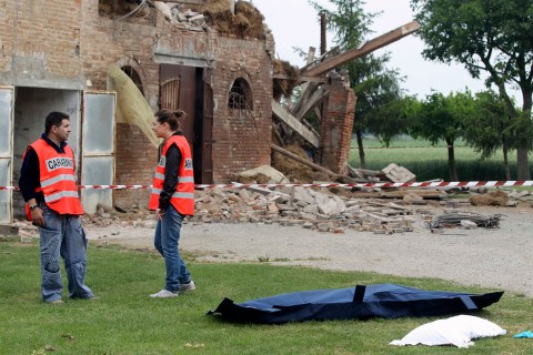 Carabinieri paramilitary police officers stand beside the body of a woman after an earthquake in Sant' Agostino