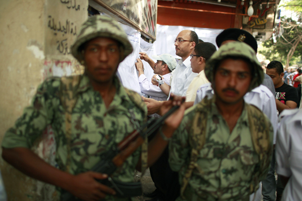 People search for their names as soldiers stand guard outside a polling station in Cairo