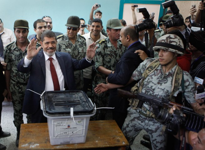 image: Egyptian presidential candidate Mohamed Morsi waves after he casts his vote at a polling station in Zagazig, 63 miles northeast of Cairo on June 16, 2012.