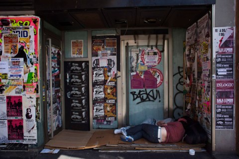 Two people sleep outside a closed down business in Madrid