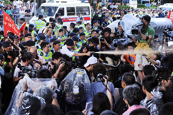 A Policeman Fires Pepper Spray at Demonstrators