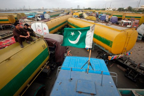 A Pakistan national flag is mounted on the top of a fuel tanker, which was used to carry fuel for NATO forces in Afghanistan, as drivers sit nearby, at a compound in Karachi