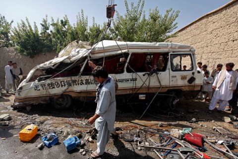 An Afghan man collects parts of a damaged bus, which was hit by a remote-controlled bomb, in the Paghman district of Kabul