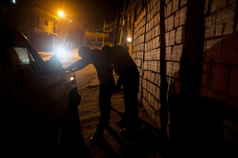 Venezuelan policemen frisk a man in Petare shantytown in Caracas.