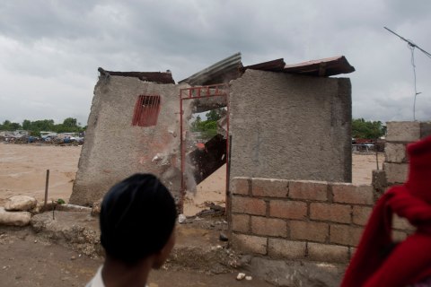 Residents look at a damaged house on the shore of a river after heavy rains brought by Hurricane Sandy in Port-au-Prince, Haiti, on Oct. 25, 2012.