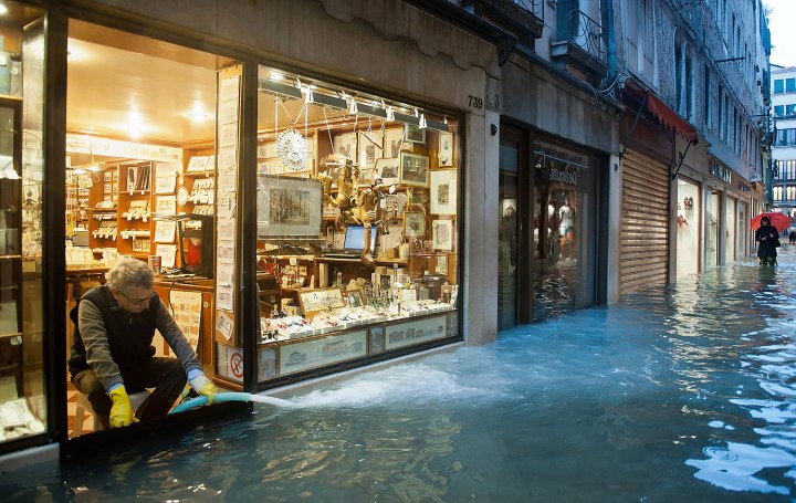 A man tries to keep the water level inside his shop at a minimum