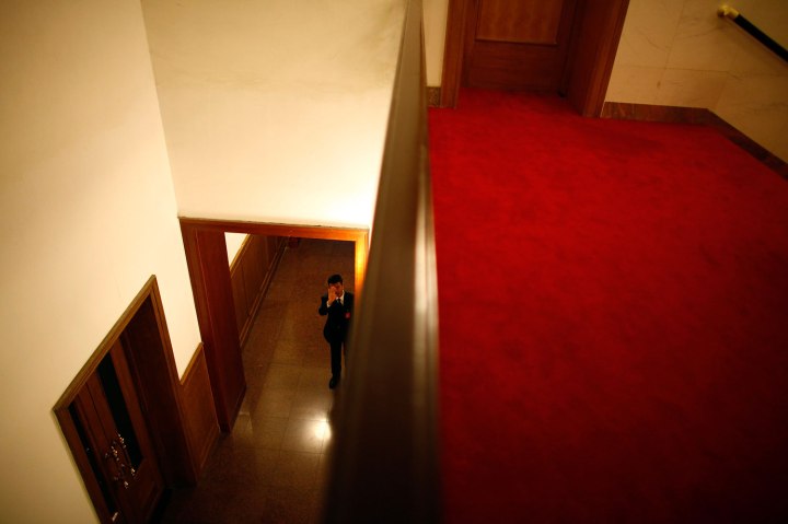 A security personnel reacts as he guards a door at the Great Hall of the People