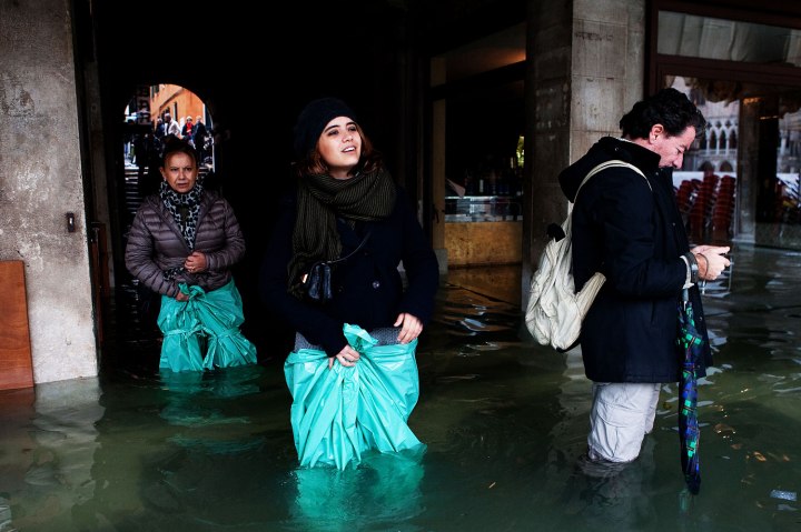 Residents and tourists wear protective clothing as exceptionally high tide floods Venice