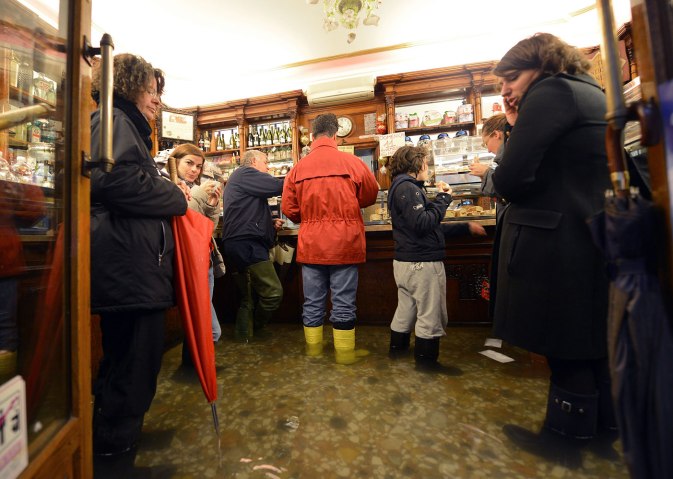 People get coffee in a flooded shop during "acqua alta" in Venice on Nov. 11, 2012
