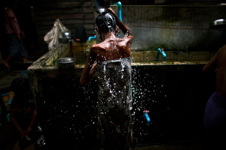 An HIV-infected patient scoops water over her head to cool down on a hot summer day at an HIV/AIDS hospice on the outskirts of Yangon, Myanmar. 