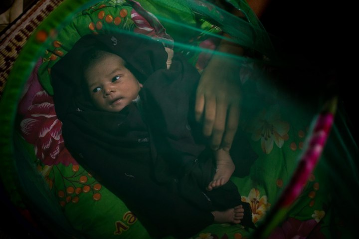 An HIV-infected mother adjusts the blanket for her seven-day-old newborn baby