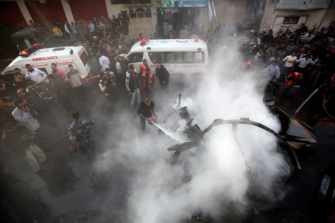 image: Palestinians extinguish the fire after an Israeli air strike on a car carrying Hamas's military chief Ahmed Al-Jaabari in Gaza City, Nov. 14, 2012. 