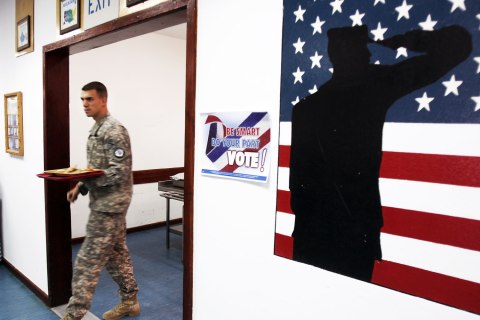 U.S. Army soldier, member of the NATO-led peacekeeping force in Kosovo, passes by a poster urging them to vote