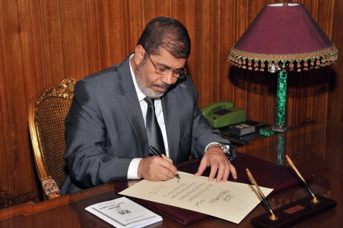 image: An image released by the Egyptian Presidency shows President Mohamed Morsi at his office in the presidential palace in Cairo on Dec. 26, 2012, as he signs a new constitution.