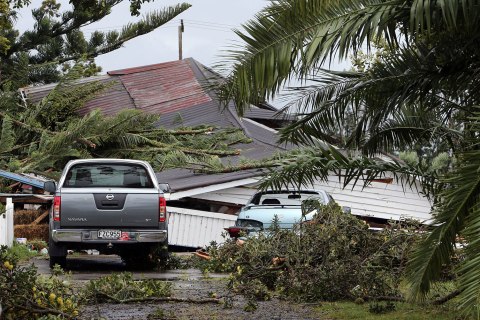 image: Cars and fallen trees surround the front of a damaged house after packed wind gusts of up to 110 kilometres (70 miles) per hour, struck suburban in Hobsonville, Auckland, Dec. 6, 2012.