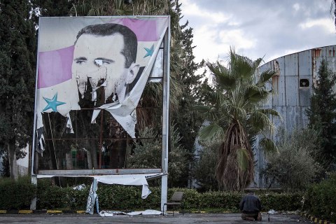 image: A Free Syrian Army fighter offers evening prayers beside a damaged poster of Syria’s President Bashar Assad during heavy clashes with government forces in Aleppo, Dec. 8, 2012.