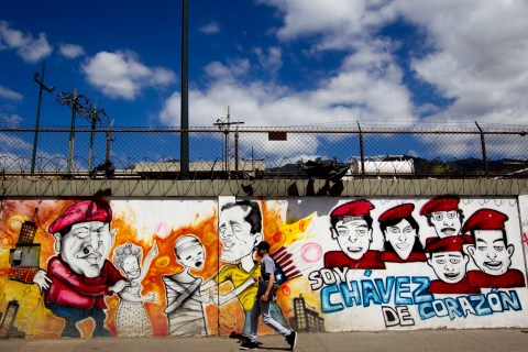 A man walks past a mural depicting Venezuelan President Chavez in Caracas