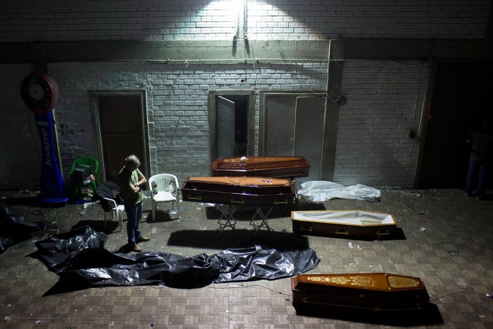 A man stands around coffins containing the remains of victims after the bodies were identified at a gymnasium in Santa Maria city, Brazil, Jan. 27, 2013. 