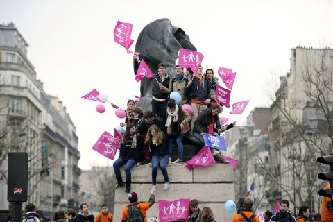 image: Young protesters hold placards on top of a statue at the start of a march against same-sex marriage at Denfert-Rochereau square in Paris, Jan. 13, 2013. 