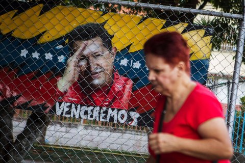 image: A woman walks next to a graffit painting of Venezuelan president Hugo Chavez in Caracas, Venezuela, on Jan. 2, 2013. 