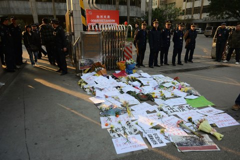 image: Security guards stand near protest banners and flowers laid outside the headquarters of Southern Weekly newspaper in Guangzhou, Guangdong province, China, Jan. 7, 2013.