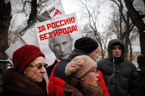 image: People carry posters of Russian President Vladimir Putin with the words reading "For Russia without Herod!" during a protest rally against the adoption ban in Moscow, Jan. 13, 2013. 