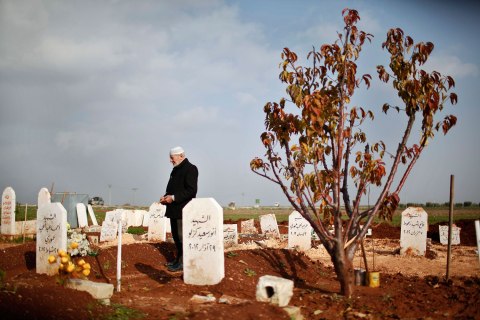 image: Abdlhamid Haj Omar, 70, a father who lost three sons and two grandsons in the ongoing Syrian crisis, prays as he visits their graves at the Martyrs' cemetery in Azaz city, North Aleppo, Dec. 25, 2012.