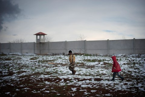 image: A Syrian refugee child helps a man to collect wood at a refugee camp in Bab al-Salam on the Syria-Turkey border, Jan. 9, 2013. 