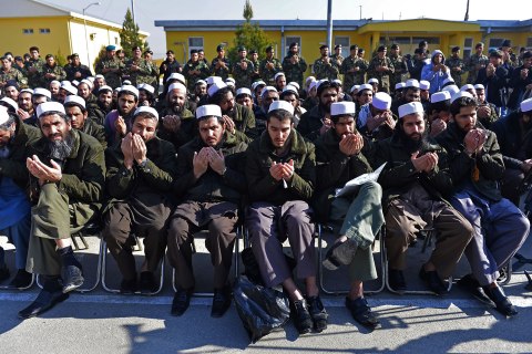 image: Released Taliban prisoners sit on chairs and pray during a ceremony in Pul-e-Charkhi jail while Afghanistan National Army soldiers look, Jan. 4, 2013. 