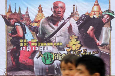 image: Pedestrians walk past a poster of the movie, "Lost in Thailand," at a cinema in Nantong city, China, Dec. 16, 2012.