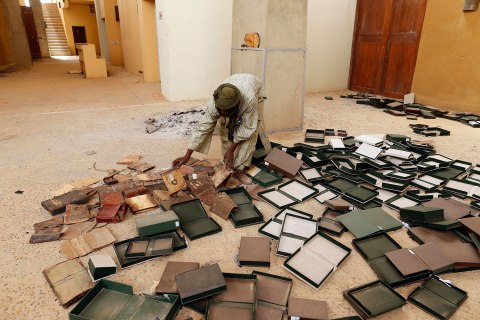 A museum guard picks up boxes holding ancient manuscripts, which were partially damaged by Islamist rebels, at the Ahmed Baba Institute in Timbuktu Jan. 31, 2013.