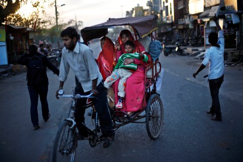 An Indian protester, right, shouts slogans as a rickshaw carrying passengers rides past during a protest against the rape of a 7-year-old girl in New Delhi.