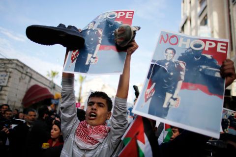 A Palestinian demonstrator holds shoes and a digitally manipulated placard depicting U.S. President Obama during a protest in Ramallah.