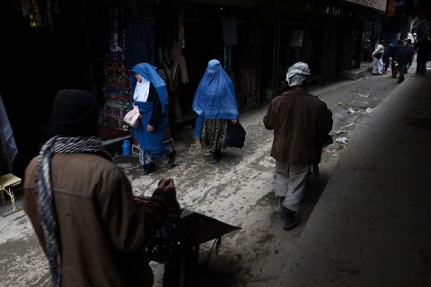 Afghan women and labourers with wheelbarrows walk down a lane in Kabul on Feb. 19, 2013.