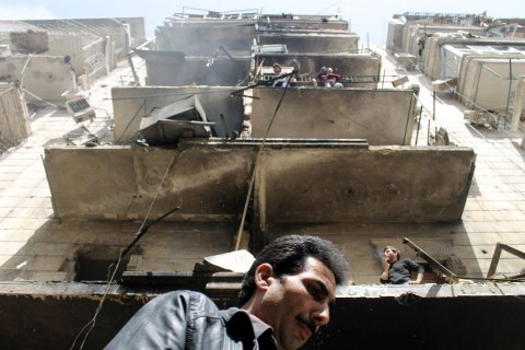 People stand at a damaged building in Al-Sukkari neighborhood, by what activists said was a result of an airstrike by the Syrian Regime, in Aleppo April 7, 2013.