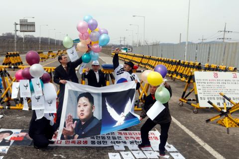 A group of anti-North Korean protesters release balloons with peace messages during a protest to denounce the North as they hold a placard showing a portrait of North Korean leader Kim Jong-Un in Paju.