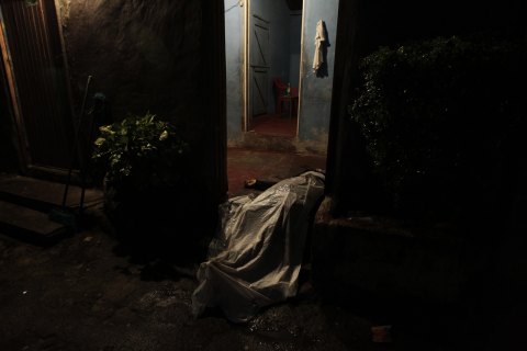 Covered-up body of man killed in shoot-out between members of Mara 18 street gang and police and military during anti-drug operation lies in house entrance in San Pedro Sula