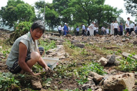 A villager sits in front of her damaged house in Zhoushan, China, Aug. 10, 2012.