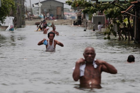Filipino men wade through chest-deep floods at Malabon city, north of Manila, Aug. 1, 2012.